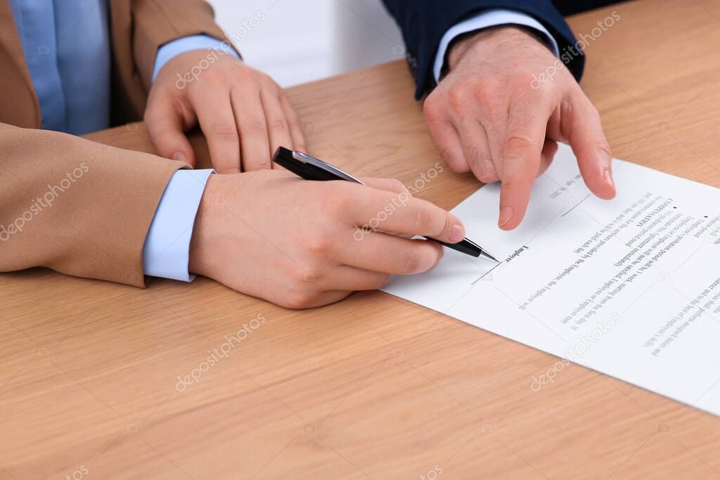manos firmando contrato en una mesa