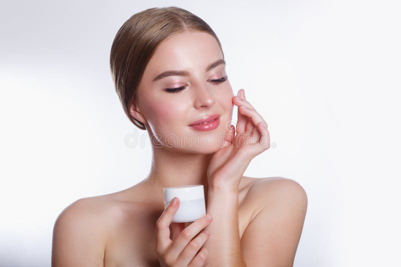 mujer aplicando crema facial en su rostro